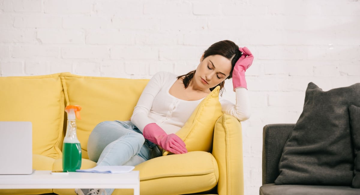 What is a Fibromyalgia Flare-Up An image of a woman in cleaning gloves collapsed on a sofa