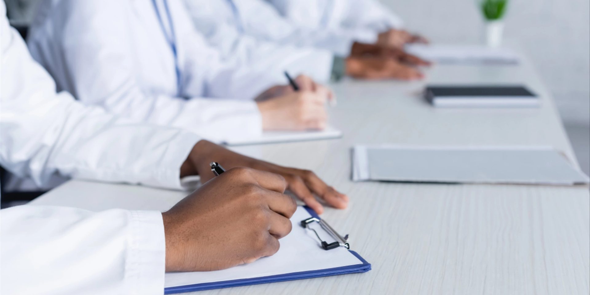 An in of a few doctors in a row zoomed in on them writing on clipboards: Call the Doctor